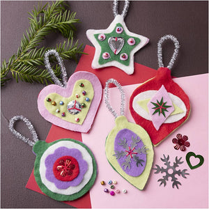 Colorful felt Christmas ornaments on a pink surface with greenery.