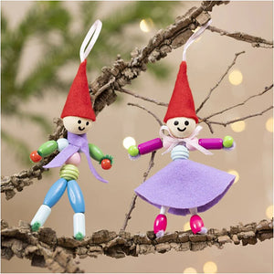 Two colorful elf figurines on a branch with blurred lights in the background