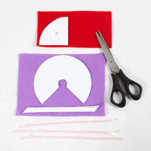 Red and purple felt shapes with white cut-out patterns and scissors on a white background