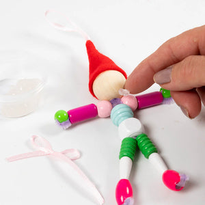 Colorful elf figurine being assembled with a hand on a white background