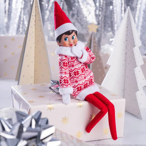 Elf  wearing the Claus Couture® Inline Sweater Dress in white and red with a fluffy polo neck sitting on a wrapped present with silver and cream wrapped presents in the background 