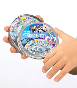 Crazy Aaron's Thinking Putty container held by a hand on a white background