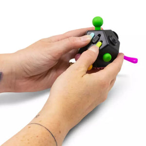 Person holding a black fidget spinner with colorful buttons on a white background