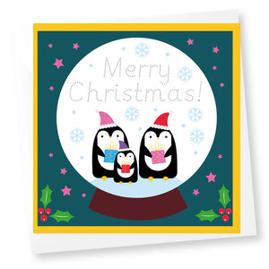 Christmas card with penguins in a snow globe and traceable writing saying 'Merry Christmas!' text on a teal background.