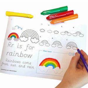 Handwriting activity book with rainbow and cloud illustrations, markers, and a hand holding a marker.