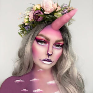 Person with unicorn makeup created with snazaroo face paint and floral headpiece on a light gray background