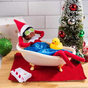 Elf on the Shelf taking a bath with a rubber duck and Christmas decorations.