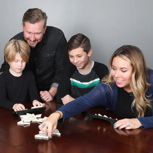 Family playing a board game together on a wooden table.